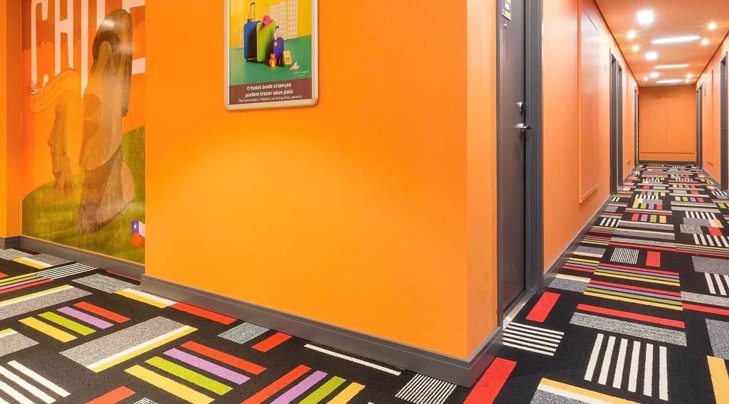 Decoração colorida aplicada com cores opostas no corredor de um hotel.