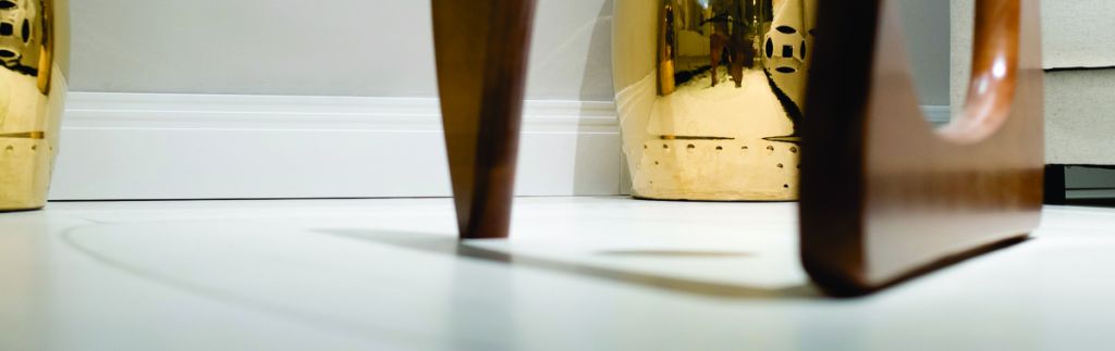 Vista dos pés de uma cadeira em uma sala com acabamento de piso decorado em tons claros.