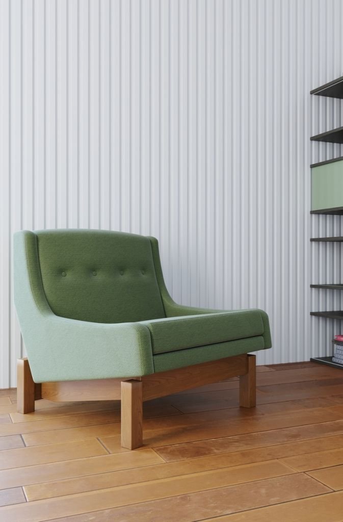 Espaço com uma poltrona verde e marrom, estante de livros ao fundo e uma parede de ripas e filetes de madeira branca.