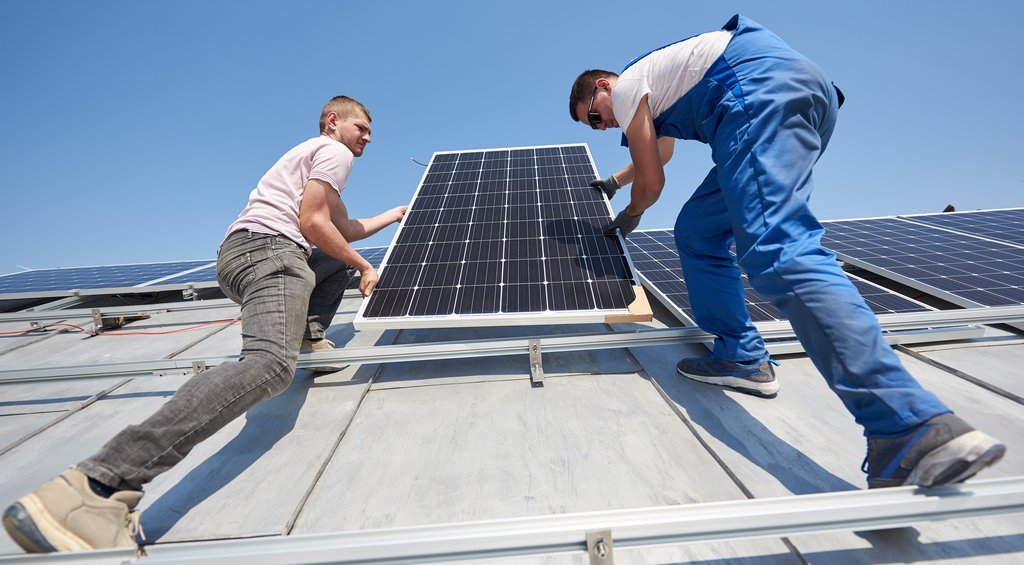Homens instalando painéis solares para captar a energia fotovoltaica