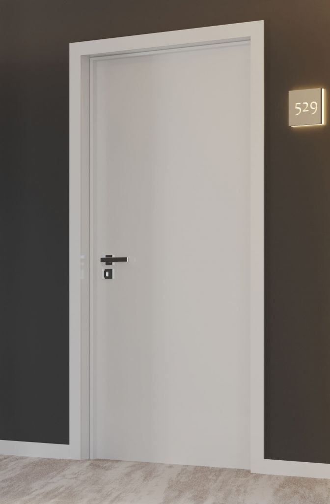 Uma porta branca, com rodapé e guarnição brancos instalados em uma parede cinza chumbo.