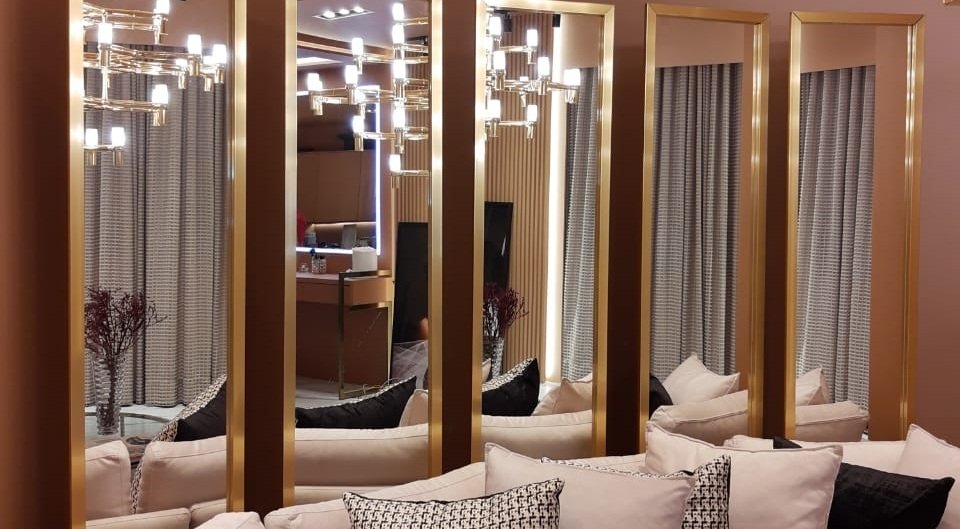 Uso de espelhos dourado em uma sala de estar, seguindo a tendência de decoração para 2022.