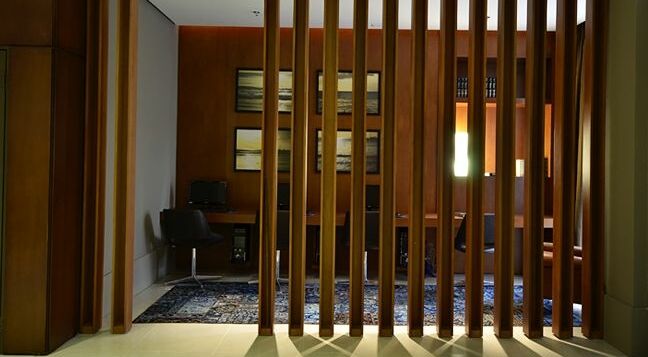 Ideia para dividir ambientes separando um espaço para o home office com divisórias de madeira.