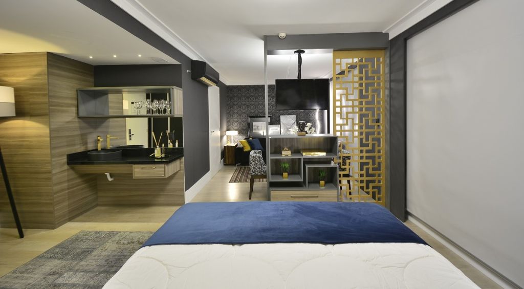Ideia para dividir ambientes integrando o quarto com a suíte em um ambiente decorado em tons de azul, branco e amarelo.