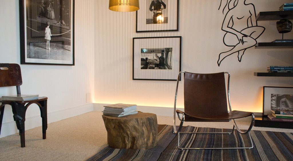 Ambiente decorado no estilo moderno, com uma poltrona na cor marrom e uma mesa de centro no formato de tronco, exemplificando como decorar uma casa nova.