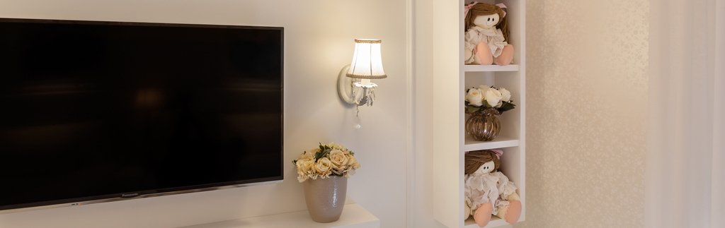 Foto de um painel de TV com estilo clássico e decorado com bichos de pelúcia e vasos. Simbolizando como escolher um painel para TV.