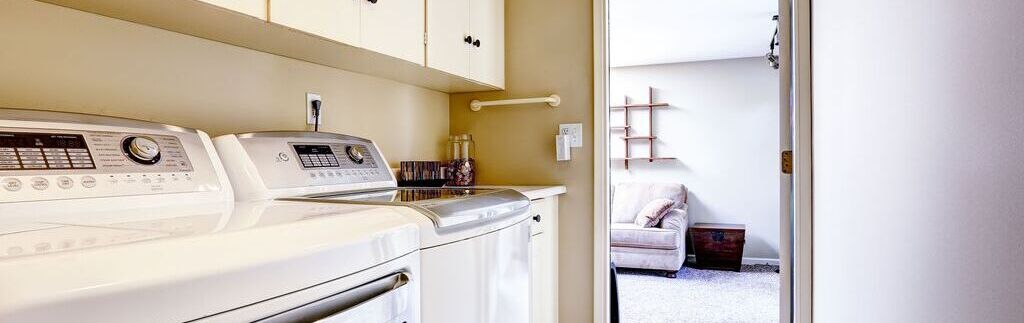 Área de serviço pequena com armários suspensos e máquinas de lavar e secar.
