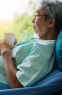 Homem idoso asiático em cama de hospital simbolizando o projeto hospitalar de construção.