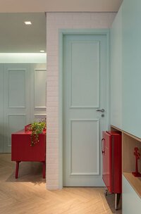 Bauhaus na decoração de hotéis: imagem mostra sala com porta azul, decorada com boiseries.