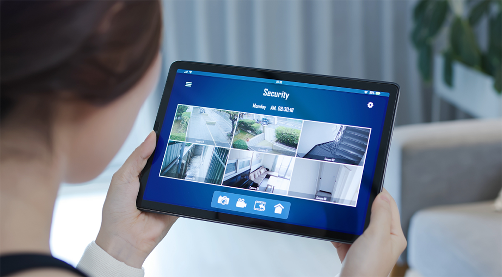 Mulher checando câmeras de segurança residenciais no tablet, usanso automação residencial.