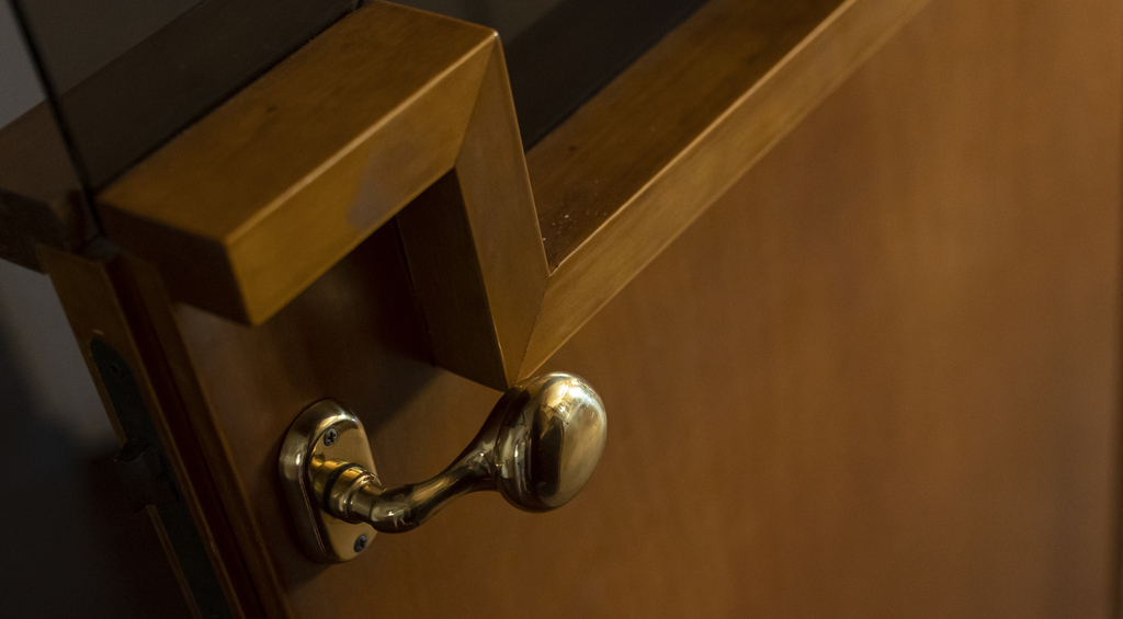 Maçaneta estrategicamente posicionada em uma porta de madeira com texturas retas embutidas.