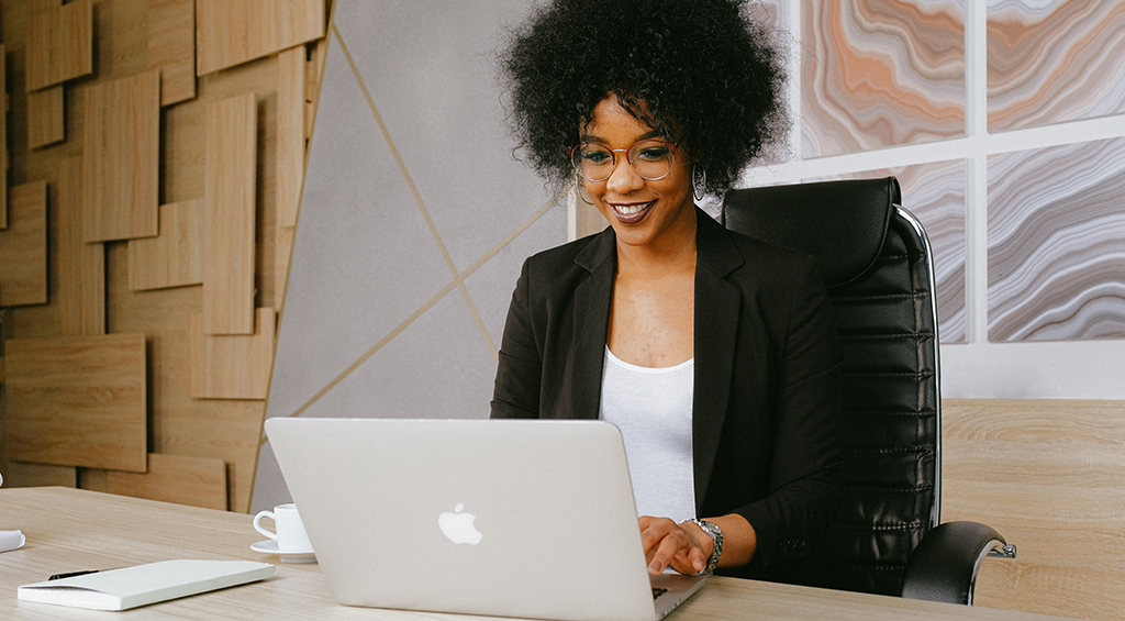 Mulher usando um laptop da Apple, e possivelmente lendo sobre o selo PBQP-H.