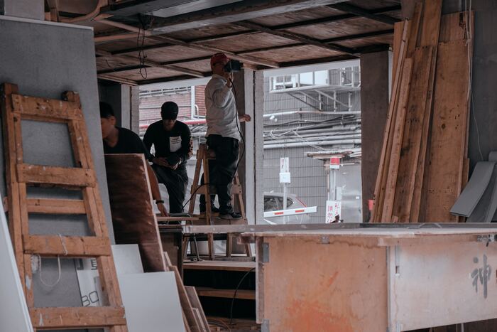 Homens em uma obra aplicando parede de drywall.